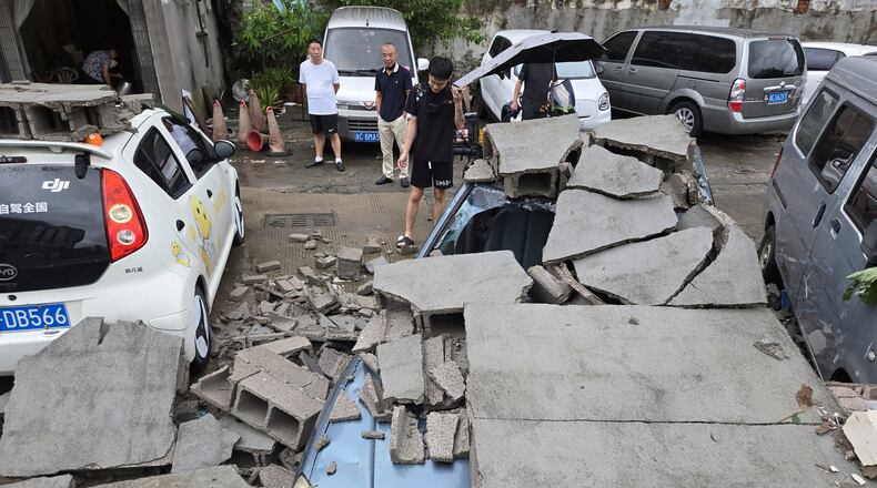 Residents view cars damaged by a fallen wall in the aftermath of Typhoon Dolphin in Wenzhou in eastern China's Zhejiang province, Monday, Aug. 10, 2026. (Chinatopix via AP)