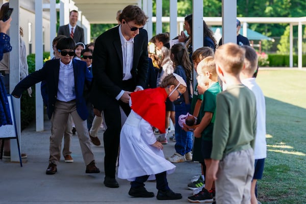 Pope David, second grader David Levergood, gives a kiss to a baby doll after being elected as the new pope during a mock papal conclave at Pinecrest Academy on May 6, 2025. (Miguel Martinez/AJC)