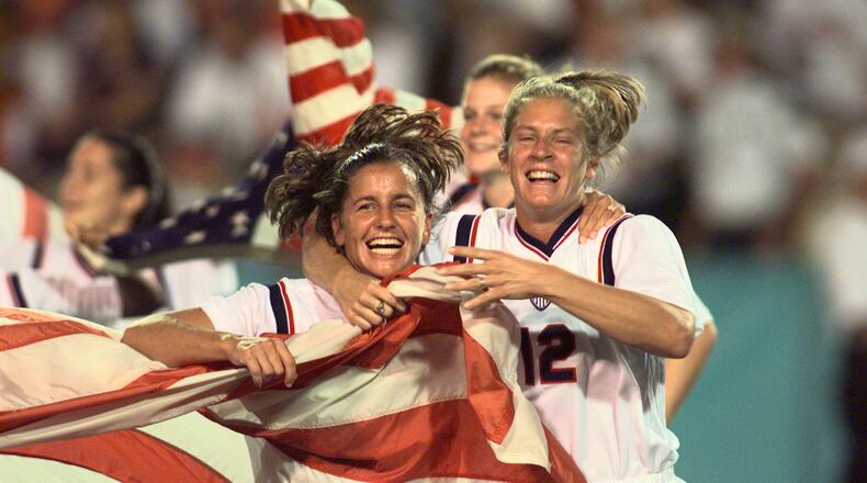 Joy Fawcett (left) and Carin Gabarra (right) run around Sanford Stadium in Athens with an American flag after their historic 2-1 gold medal win over China during the 1996 Summer Olympic Games. (David Tulis/AJC)