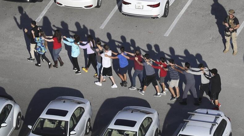People are brought out of Marjory Stoneman Douglas High School after a shooting at the school on Feb. 14. (Joe Raedle / Getty Images)