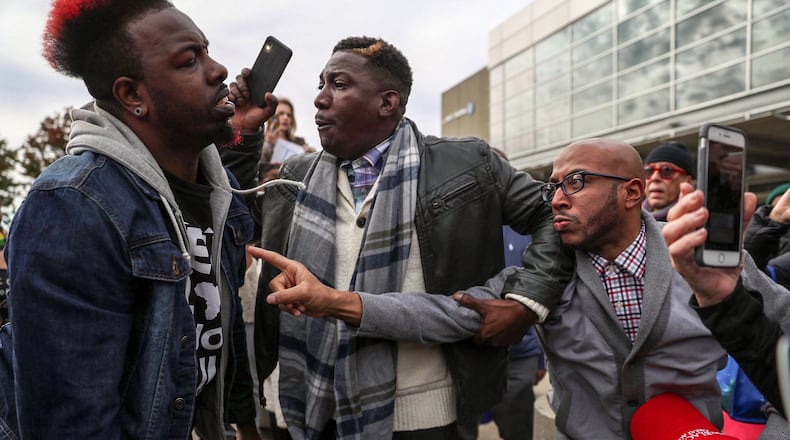 President Donald Trump supporters Tony Smith (right) of College Park and Jerrod Brown (center) of Savannah, get in a verbal shouting match with Anti-Trump protestor Chris Mungin (left) near the Georgia World Congress Center, Friday, November 8, 2019. (Alyssa Pointer)