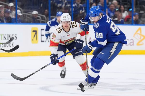 Tampa Bay Lightning defenseman J.J. Moser (90) tries to control the puck in front of Florida Panthers right wing Mackie Samoskevich (25) during the first period in Game 2 of an NHL hockey Stanley Cup first-round playoff series, Thursday, April 24, 2025, in Tampa, Fla. (AP Photo/Chris O'Meara)