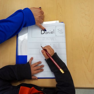 Head Start program teaching assistant Tania Ortiz helps a student practice writing his name in Miami, Jan. 29, 2025. (Rebecca Blackwell/AP)