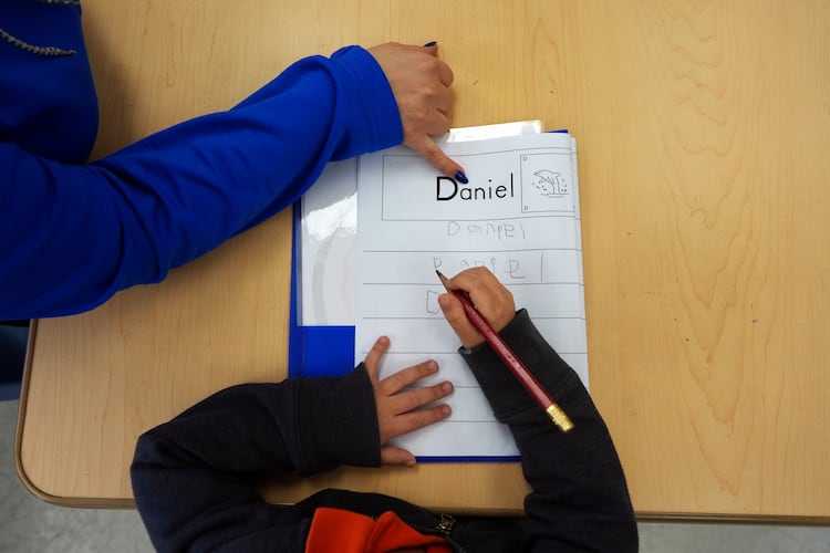 Head Start program teaching assistant Tania Ortiz helps a student practice writing his name in Miami, Jan. 29, 2025. (Rebecca Blackwell/AP)