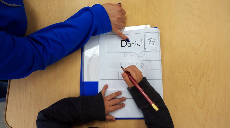 Head Start program teaching assistant Tania Ortiz helps a student practice writing his name in Miami, Jan. 29, 2025. (Rebecca Blackwell/AP)