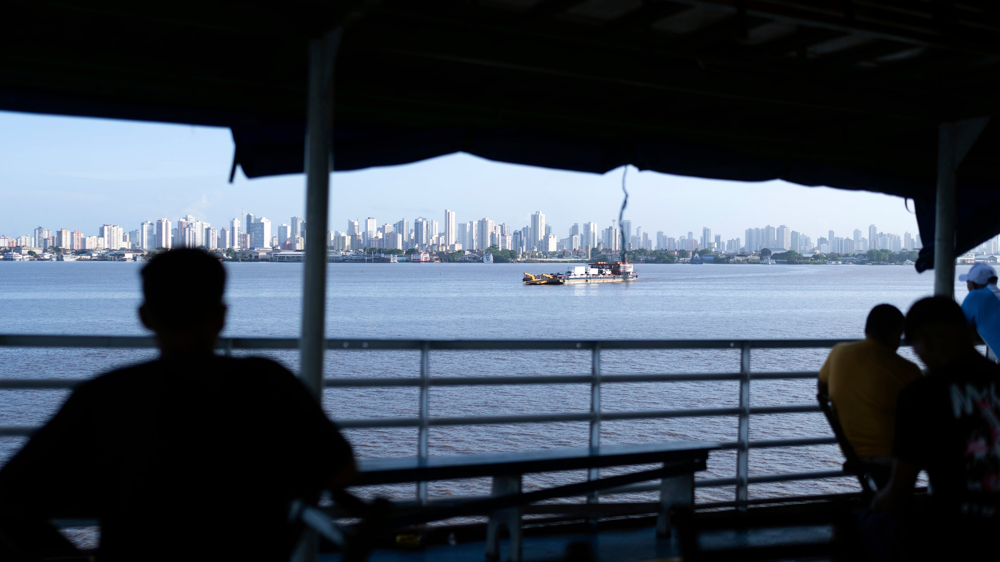 FILE - People look out at the coast of Belem, Brazil, as a boat nears shore, March 23, 2025. (AP Photo/Jorge Saenz, File)