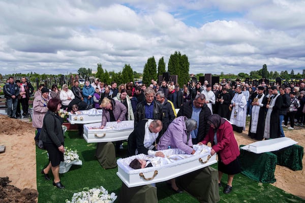 Relatives say goodbye to children Roman Martyniuk, 17, Tamara Martyniuk, 8, and Stanislav Martyniuk, 12, killed in a Russian strike on Sunday, during farewell ceremony in Korostyshiv, Zhytomyr region, Ukraine, Wednesday, May 28, 2025. (AP Photo/Evgeniy Maloletka)