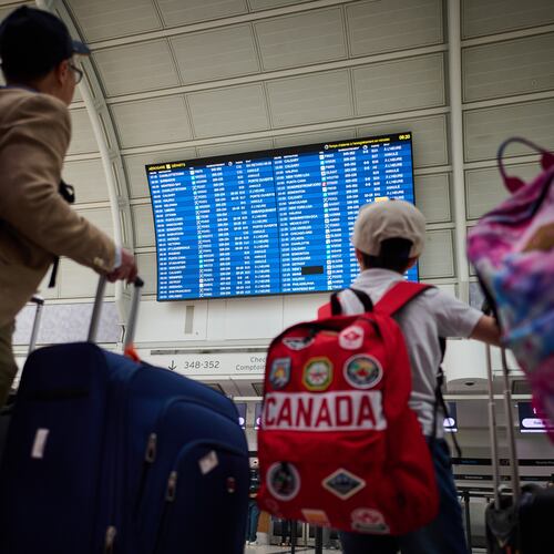 Travelers look at departures by the WestJet gate as the airline's flight attendants strike outside at Pearson International Airport in Toronto, on Sunday, Aug. 2, 2026. (Sammy Kogan/The Canadian Press via AP)