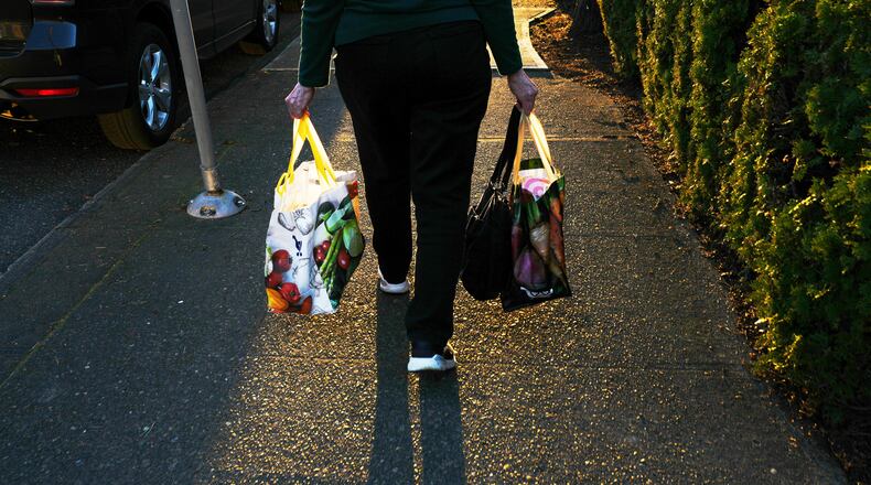 FILE - A woman carries reuable shopping bags to her car on Monday, March 16, 2026, in Portland, Ore. (AP Photo/Jenny Kane, File)