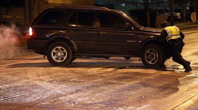 Atlanta Police Officer N. Bays tries to help straighten out an SUV that spun out on the ice at the intersection of Spring Street and 16th Street in Midtown on Tuesday evening Jan. 7, 2014. BEN GRAY / BGRAY@AJC.COM
