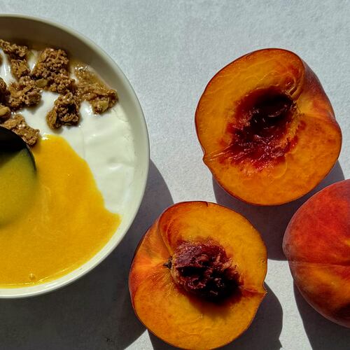 Peach curd being spooned over yogurt and granola.