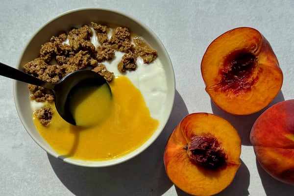 Peach curd being spooned over yogurt and granola.