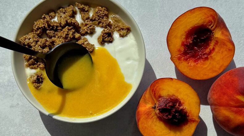 Peach curd being spooned over yogurt and granola.