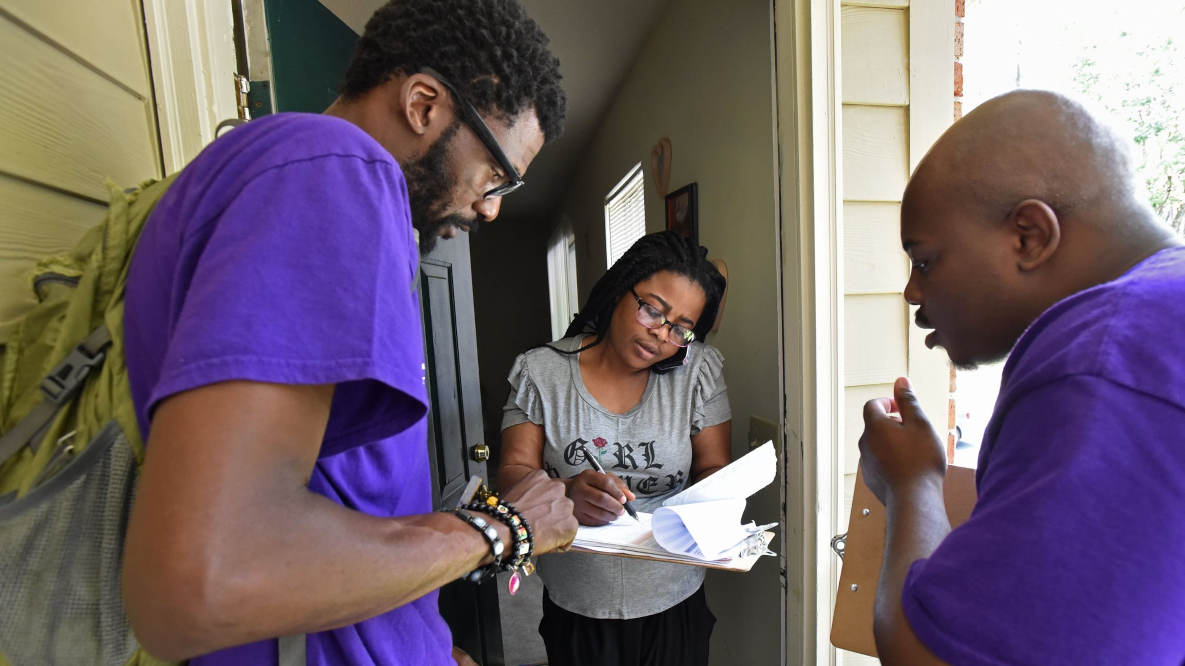 Rodney King (left), volunteer with New Georgia Project, and Corbin Spencer (right), field director of New Georgia Project, help Rueke Uyunwa register to vote in 2017. (Hyosub Shin/AJC)
