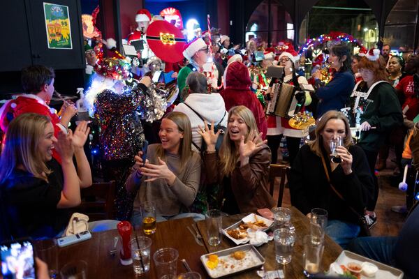 Bargoers delight in the festive environment as members of the Seed & Feed Marching Abominable play inside Little Five Pub during Atl SantaCon on Saturday, Dec. 20, 2025. (Ben Gray for the AJC)