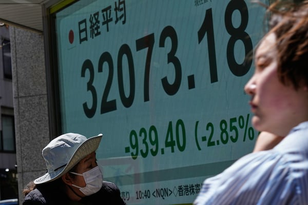 People walk past monitors showing Japan's Nikkei 225 index at a securities firm in Tokyo, Wednesday, April 9, 2025. (AP Photo/Hiro Komae)