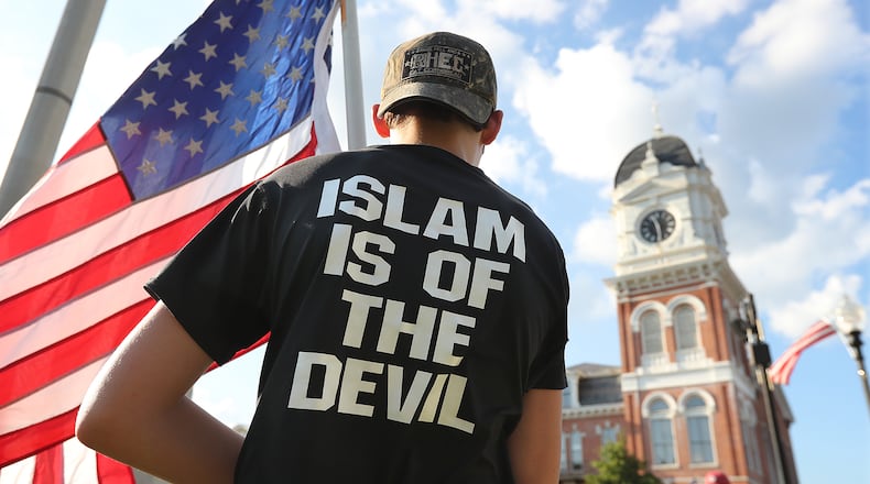 A young man stands across from the Covington courthouse during a protest organized by the III% Georgia Security Force against building a mosque in Newton County held on the town square, Tuesday, Sept. 13, 2016, in Covington. Curtis Compton /ccompton@ajc.com