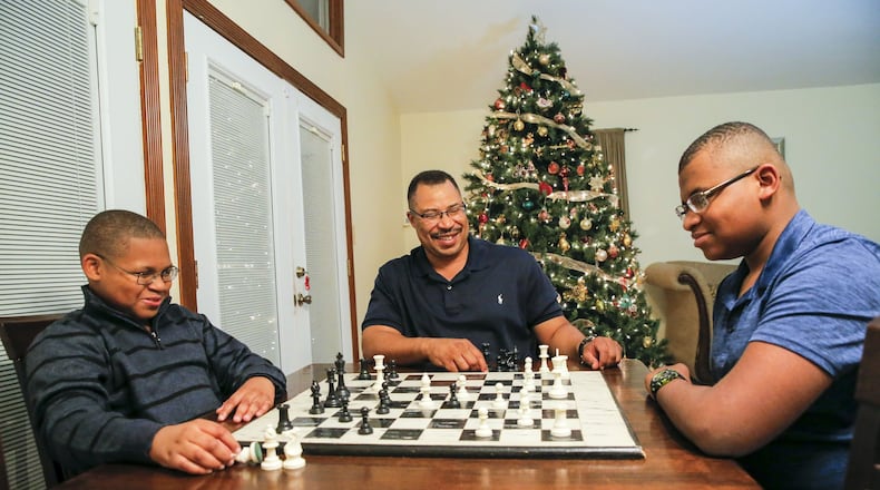 Corey McDaniel (middle) coaches his sons Corey Jr. (right), 14, and Christian, 11, in a game of chess at their Stone Mountain home this week. Corey, a single dad, lost his wife, Allison McDaniel, when she died suddenly after suffering complications from a seizure in 2016. ALYSSA POINTER / ALYSSA.POINTER@AJC.COM