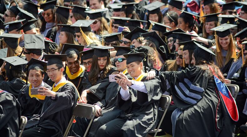 Graduates pause to make selfie pictures during commencement.