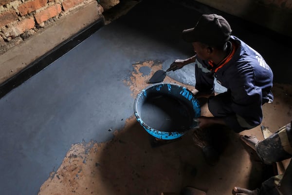Alex Wanda, a construction officer at EarthEnable, installs paste on floors May 17, 2025, in Jinja, Uganda. (AP Photo/Hajarah Nalwadda)