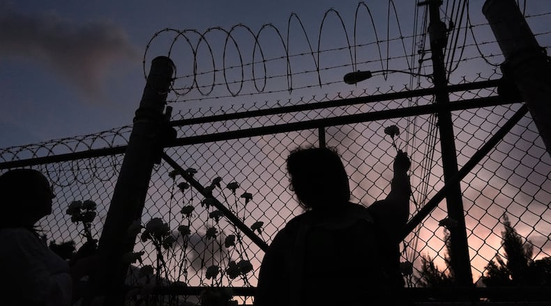 FILE - People place flowers on a fence outside Krome Detention Center in Miami, Saturday, May 24, 2025, during a vigil to recognize people who have died in U.S. Immigration and Customs Enforcement custody as well as those affected by mass deportations. (AP Photo/Rebecca Blackwell, File)
