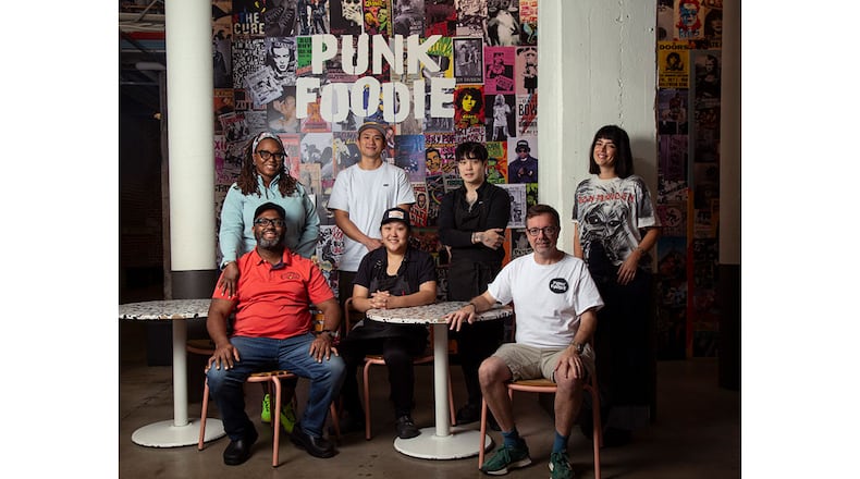 Punk Foodie founder Sam Flemming (front row right) with pop-up chefs at the Punk Foodie stall at Ponce City Market including (left to right) Jimmie Jackson and Phya J. of JJC Jimmie Jerk Chicken;  Fu-Mao Sun of Mighty Hans and Jess Kim (center seated) and Jun Park (standing) of Ganji; Sam Flemming of Punk Foodie; Designer Alynn Martinez .   (MARTHA WILLIAMS FOR THE ATLANTA JOURNAL-CONSTITUTION)