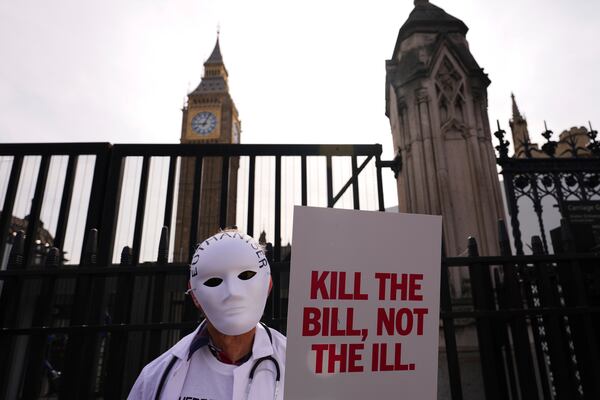 A demonstrator against assisted dying holds a banner outside Parliament in London, Friday, June 20, 2025, as British lawmakers are set to vote Friday on whether to back a bill to help terminally ill adults end their lives in England and Wales. (AP Photo/Kirsty Wigglesworth)