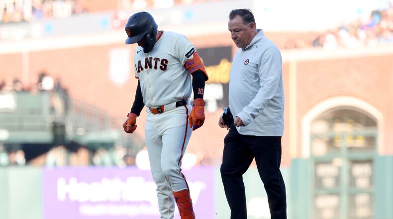 San Francisco Giants' Casey Schmitt, left, walks off the field with an injury accompanied by athletic trainer Dave Groeschner, right, during the second inning of a baseball game against the Milwaukee Brewers in San Francisco, Monday, July 27, 2026. (AP Photo/Jed Jacobsohn)