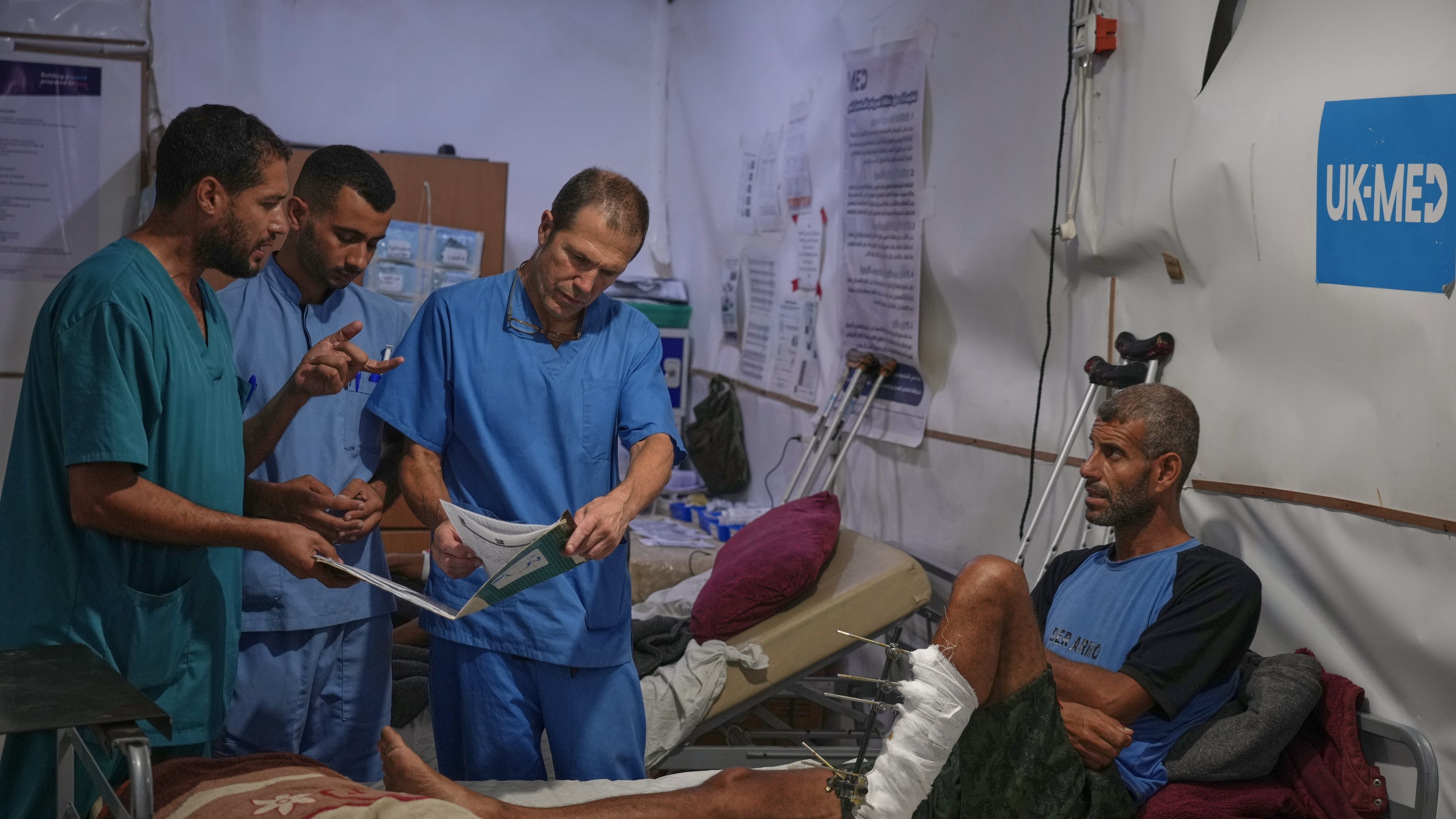 Dr. Paul Ransom of the British humanitarian medical NGO UK-Med, assisted by local medical staff, treats patients at a field hospital in Muwasi, near Khan Younis in the southern Gaza Strip, Saturday, Sept. 27, 2025. (AP Photo/Jehad Alshrafi)
