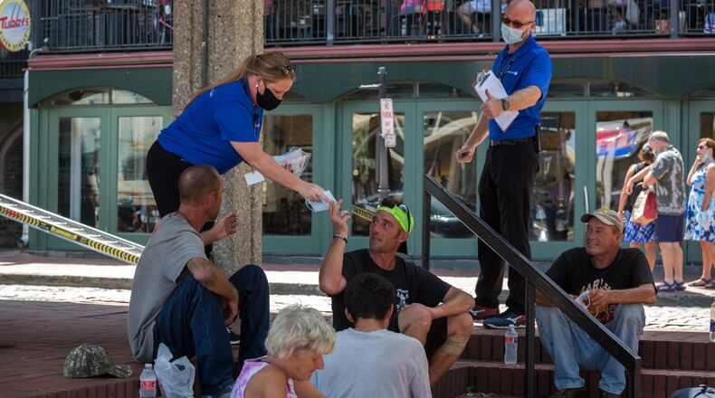 SAVANNAH, GA - Sept. 4, 2020: Members of the CoVid Resource Team, Nicole Bush, left, and Matthew Krueger, right, hand out masks to a group of people eating lunch outside. (AJC Photo/Stephen B. Morton)
