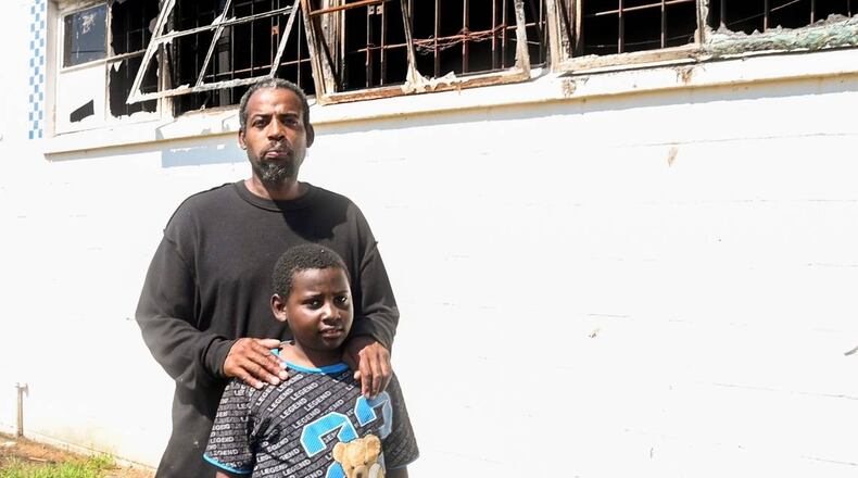 Tony Walker, and his son, 8-year-old son, Antonio, outside of what’s left of Doggie Dogs, his walk-up hot dog restaurant that was destroyed by a fire. (Photo Courtesy of Jason Vorhees/The Telegraph)