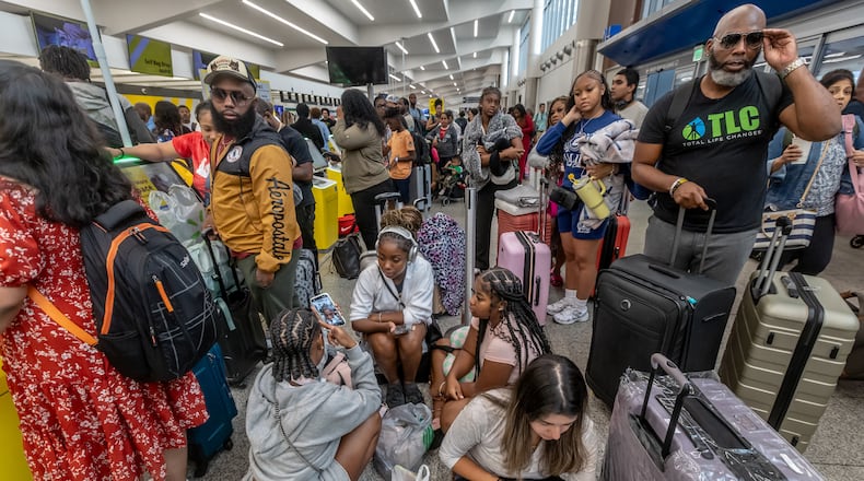Torry Wallace (right) waits with his stepdaughter’s friends and family on the North Terminal for a flight to Las Vegas for her birthday party as a massive outage is affecting Microsoft users around the globe, disrupting airlines, railways, banks, stock exchanges and other businesses. (John Spink/AJC)