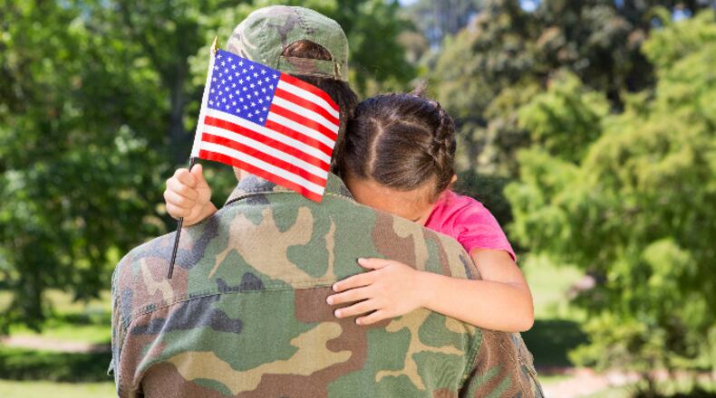 American soldier reunited with daughter on a sunny day (stock photo).
