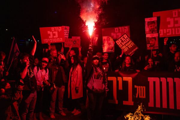 Relatives of hostages and demonstrators light flares during a protest demanding a ceasefire deal and the immediate release of hostages held by Hamas in the Gaza Strip on Sunday, March 9, 2025, in Tel Aviv, Israel. (AP Photo/Ohad Zwigenberg)