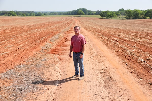 Lee Nunn stands in a newly planted cotton field in Morgan County on Thursday, April 23, 2026. Though this field is irrigated, Nunn would rather rely on rain than the costly irrigation system. (Arvin Temkar/AJC)