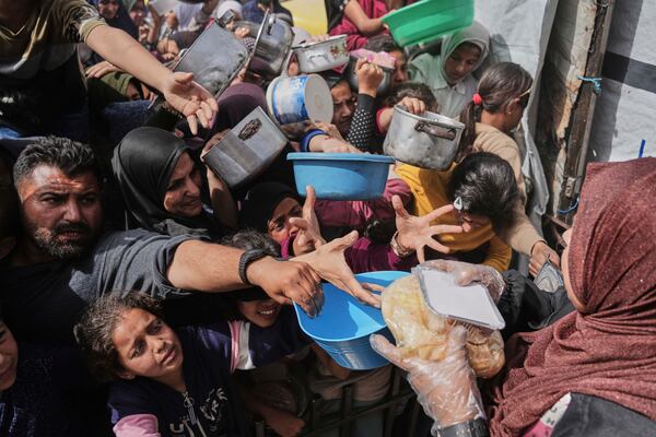 Palestinians wait to get donated food at a distribution center in Beit Lahiya in the northern Gaza Strip, Monday, April 7, 2025. (AP Photo/Jehad Alshrafi)