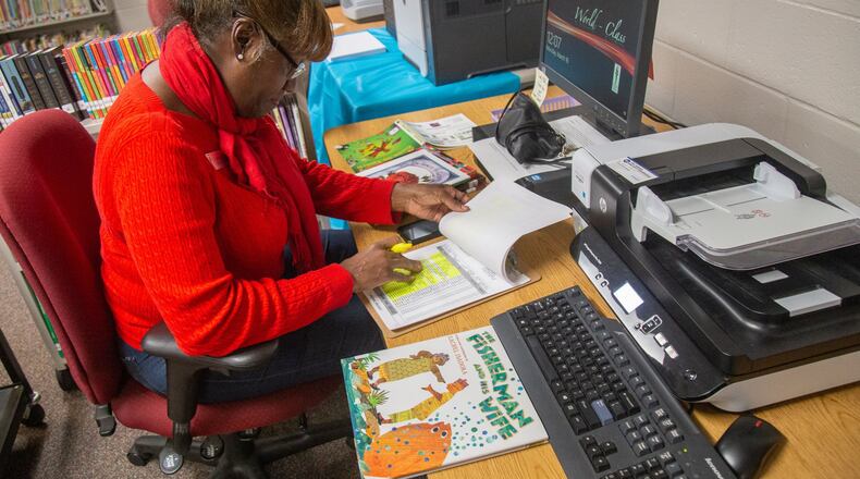 A Lilburn Elementary School stellar substitute works on cataloging new books that arrived at the school on March 16, 2020. STEVE SCHAEFER / SPECIAL TO THE AJC