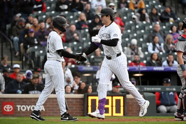 Colorado Rockies' Mickey Moniak (22) and Michael Toglia (4) celebrate after a home run by Toglia in the second inning of a baseball game against the Atlanta Braves Tuesday, April 29, 2025, in Denver. (AP Photo/Geneva Heffernan)