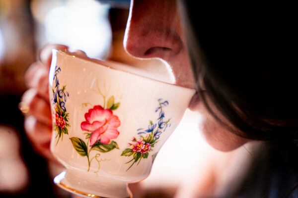 A closeup shot of part of a woman's face as she sips from a teacup with a floral motif