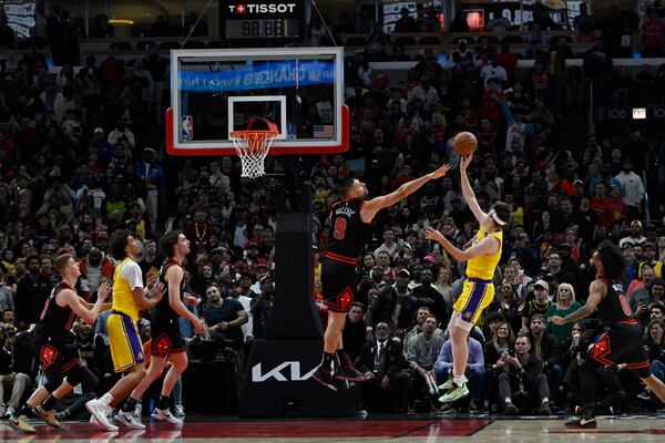 Los Angeles Lakers' Austin Reaves (15) goes up for a shot against Chicago Bulls' Nikola Vucevic (9) during the second half of an NBA game Thursday, March 27, 2025, in Chicago. (AP Photo/Paul Beaty)