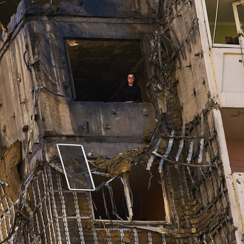 A woman peers from a window of a partially damaged residential building following a Russian drone attack in Kyiv, Ukraine, Wednesday, Sept. 9, 2026. (AP Photo/Francisco Seco)