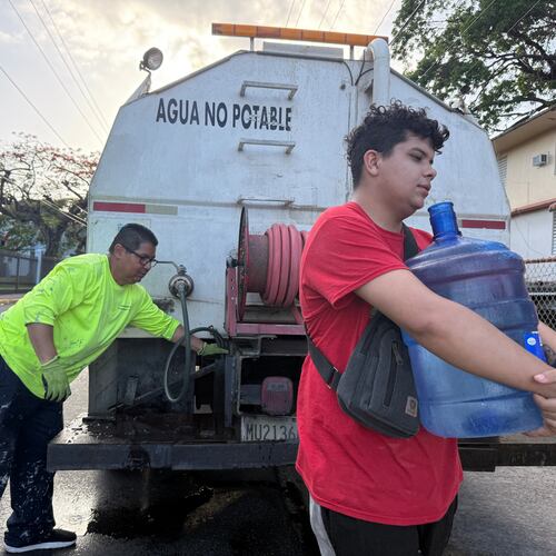 Bryan Pérez hauls a five-gallon water jug to his apartment in the Villa Kennedy public housing complex in San Juan, Puerto Rico, Wednesday, June 10, 2026. (AP Photo/Danica Coto)
