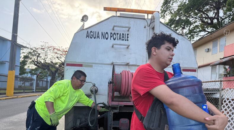Bryan Pérez hauls a five-gallon water jug to his apartment in the Villa Kennedy public housing complex in San Juan, Puerto Rico, Wednesday, June 10, 2026. (AP Photo/Danica Coto)