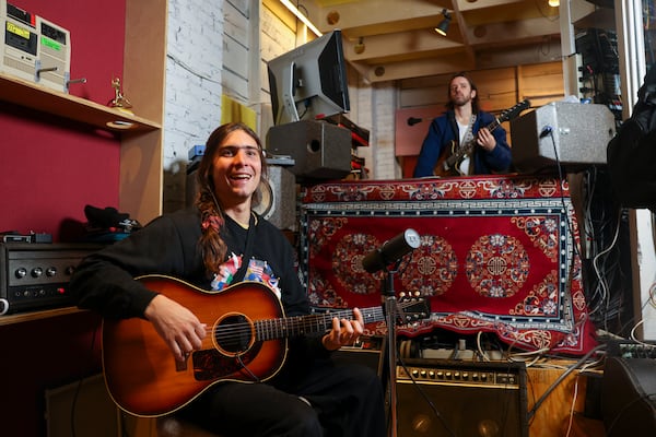 Musicians Clark Hamilton (left) and Zach Pyles of Improvement Movement practice in their basement studio. This year, the band is working on new music and gearing up to release its third album. (Jason Getz/AJC)