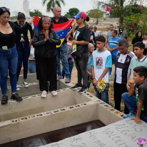 Relatives of Edilson Torres, a Venezuelan police officer who died in prison a month after being arrested on accusations of treason, gather around his grave during his funeral in Guanare, Venezuela, Tuesday, Jan. 13, 2026. (AP Photo/Ariana Cubillos)