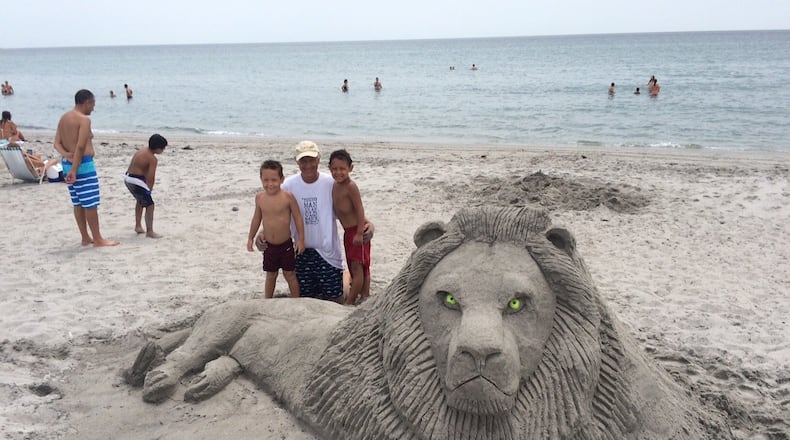 Lee Stoops poses with his grandsons, Casey and Cale, in front of his Cecil the lion sand sculpture Friday. (contributed)
