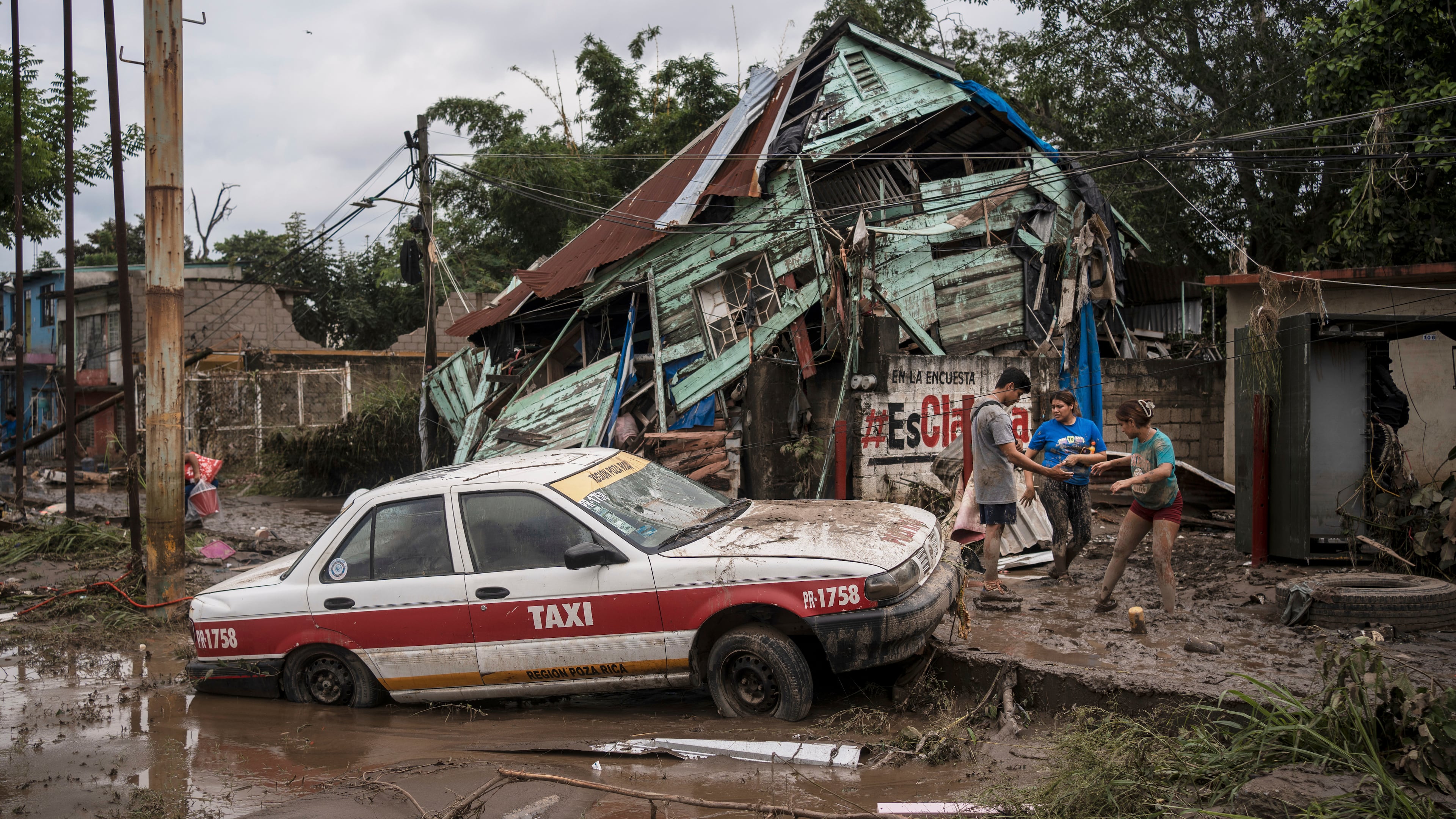Neighbors gather around a damaged house after heavy rainfall in Poza Rica, Veracruz state, Mexico, Saturday, Oct. 11, 2025. (AP Photo/Felix Marquez)