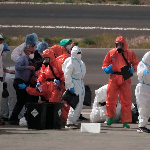 Passengers are sprayed with disinfectant by Spanish government officials before boarding a plane after disembarking from the hantavirus-stricken cruise ship MV Hondius at Tenerife airport in the Canary Islands, Spain, Sunday, May 10, 2026. (AP Photo/Arturo Rodriguez)