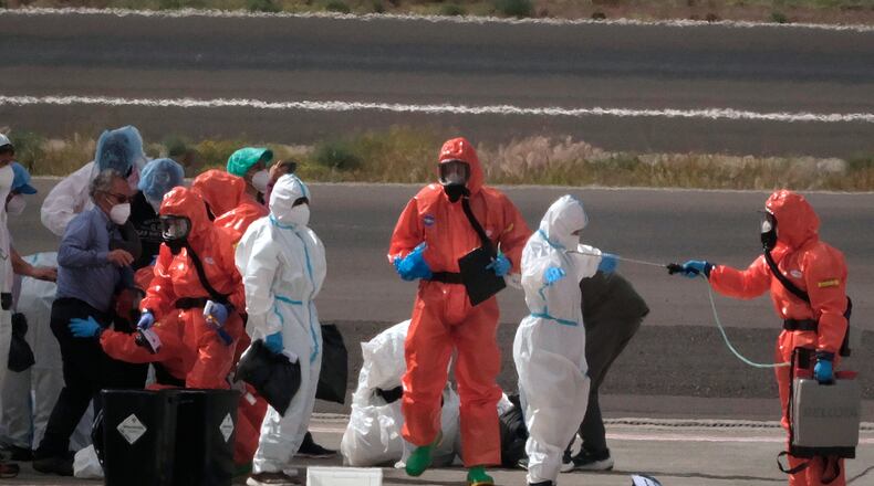 Passengers are sprayed with disinfectant by Spanish government officials before boarding a plane after disembarking from the hantavirus-stricken cruise ship MV Hondius at Tenerife airport in the Canary Islands, Spain, Sunday, May 10, 2026. (AP Photo/Arturo Rodriguez)
