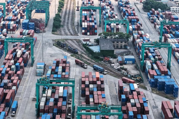 Trucks move past container pile-up at a container terminal, in Shanghai, China on Wednesday, May 14, 2025. (Chinatopix Via AP)